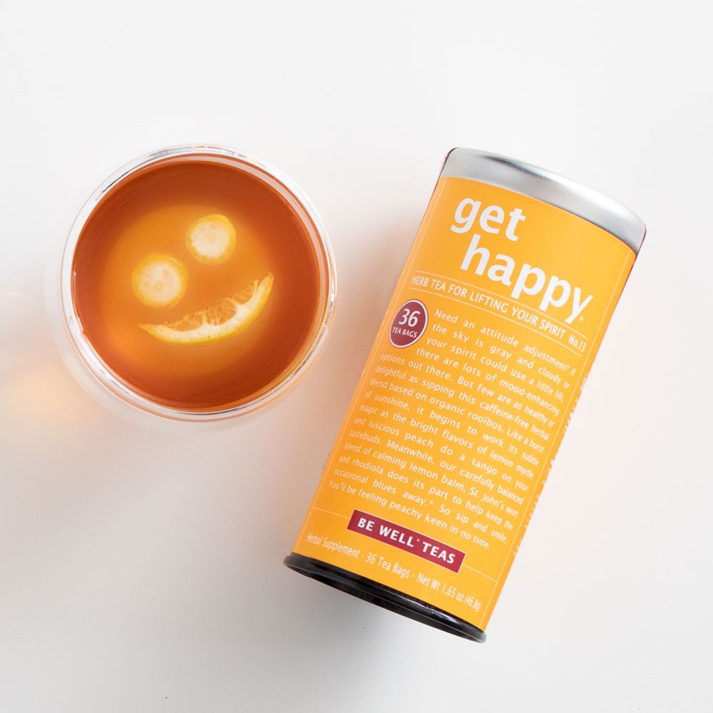 get happy red tea canister displayed next to a cup of tea with an orange inside on a white background