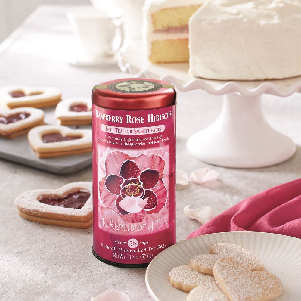 raspberry rose hibiscus herbal tea canister displayed next to cookies and cake on a cake stand