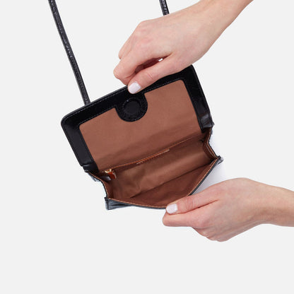 a persons hands showing the inside view of the black jill wallet crossbody on a white background