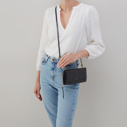 woman wearing jeans and a white blouse with a black rubie crossbody over her shoulder.