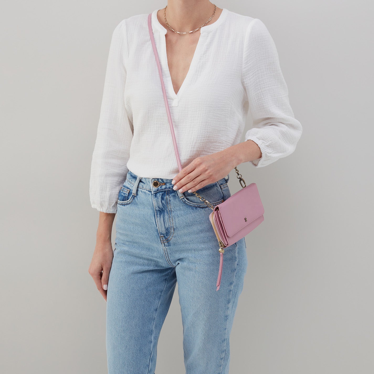 woman wearing jeans and a white blouse with a lilac rose rubie crossbody over her shoulder.