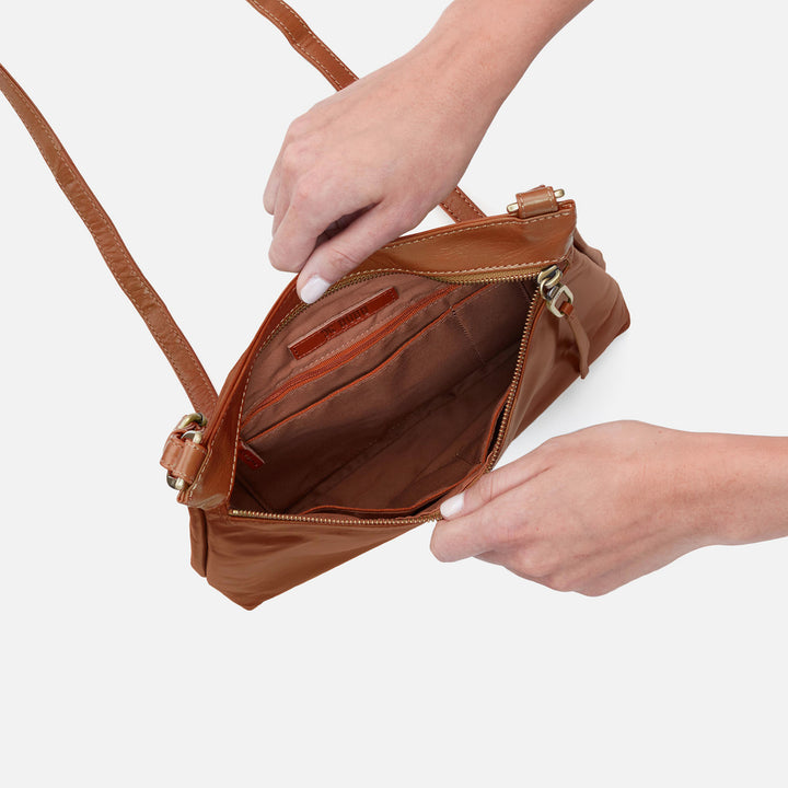 a persons hands showing the inside view of the truffle cambel crossbody on a white background