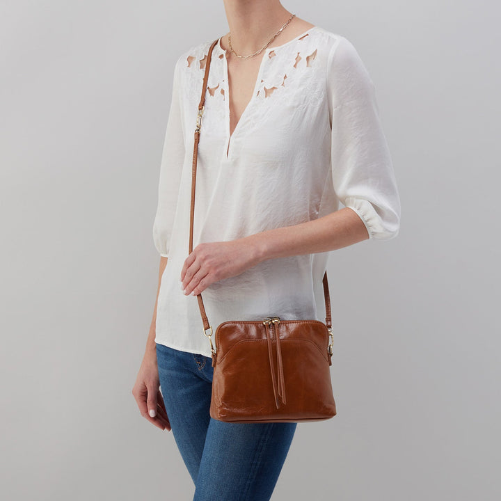 a woman wearing the truffle reeva as a crossbody against a light gray background