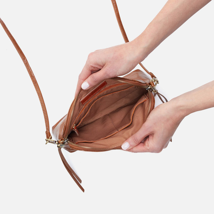 a persons hands showing the inside view of the truffle reeva crossbody on a white background