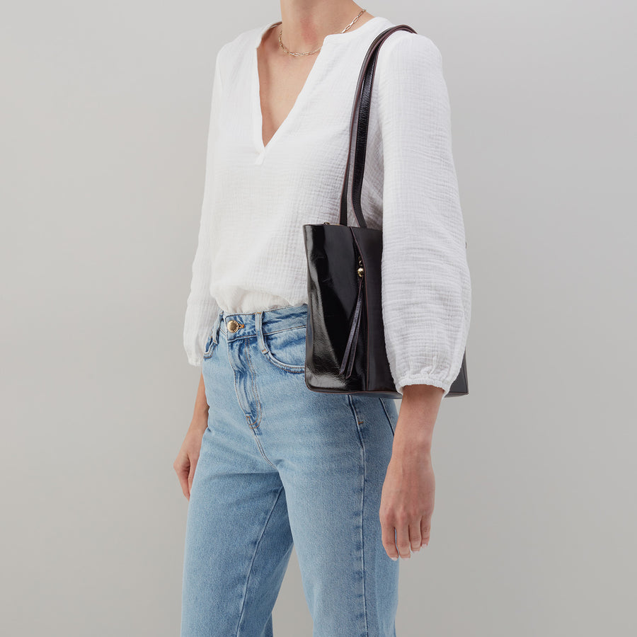 person wearing jeans and a white shirt with black haven tote on her shoulder.