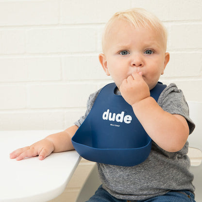 little boy sitting at a table wearing the wonder bib against a white background