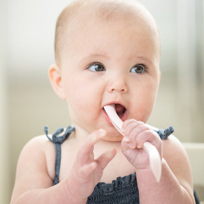 a little girl chewing on a spoon