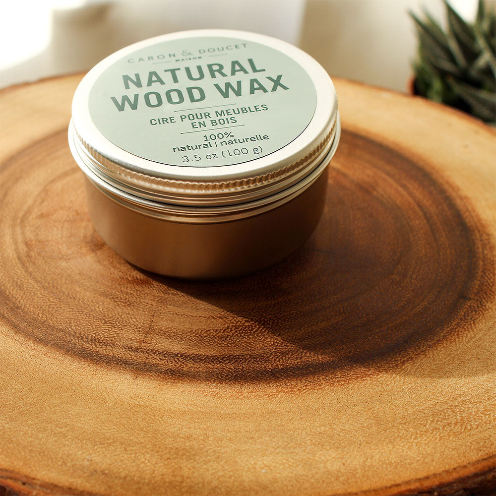 the natural wood wax tin displayed on a round piece of wood with a succulent in the background