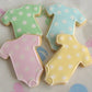 onesie shaped cookies decorated with pastel colors and dots.