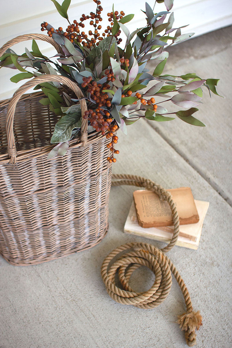 large tall oval wicker baskets displayed with greenery bunch next to knotted rope against a white slatted wall