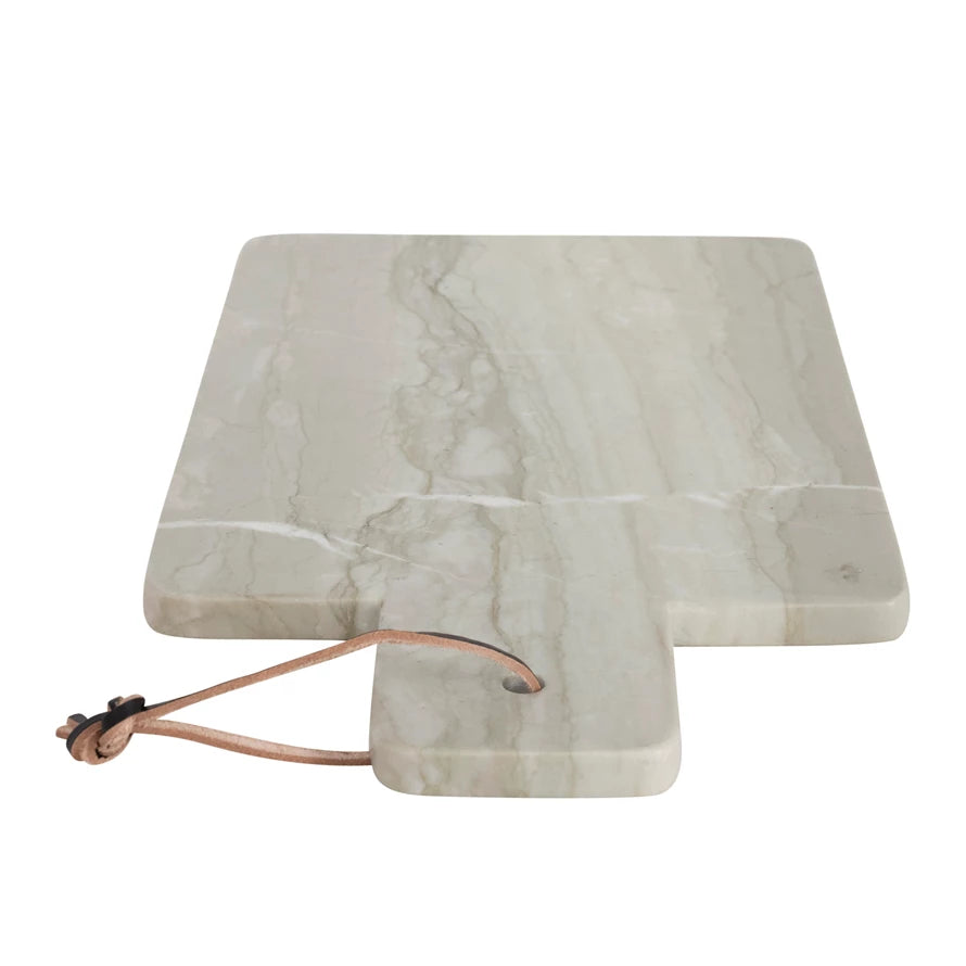 angled view of the marble cheese cutting board with leather strap on a white background