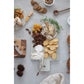 marble cheese cutting board with leather strap displayed with charcuterie foods and serving trays on a white background