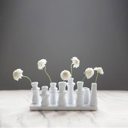 stoneware multi vase displayed with white flowers in a few displayed on a distressed white table against a gray background