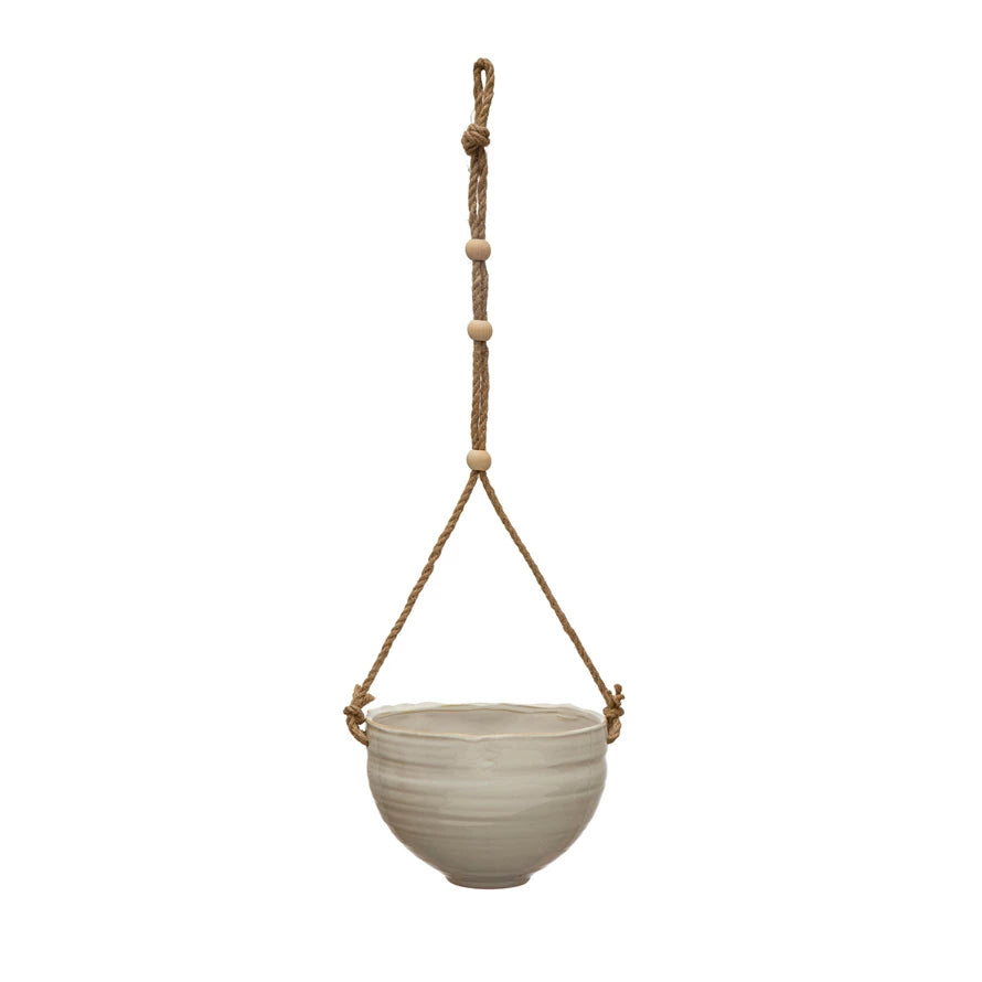 round cream colored pot hanging from jute rope with wooden beads on it.