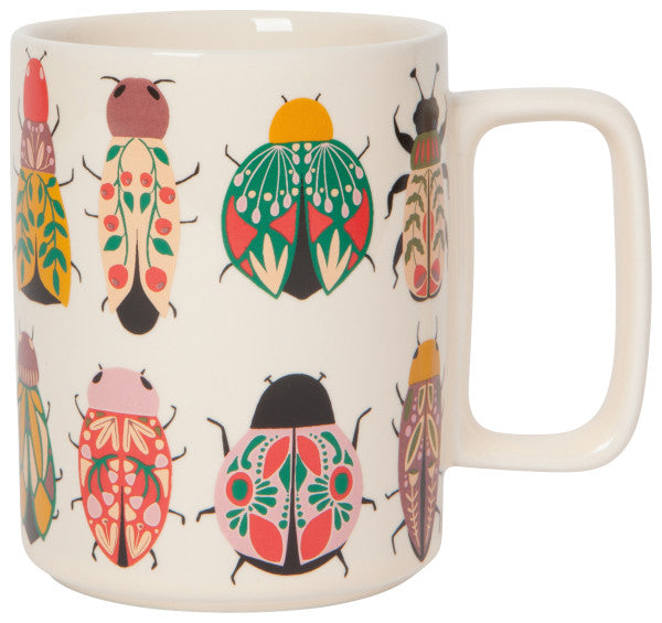 white amulet studio mug is white with scarabs and beetles in hues of pinks and greens