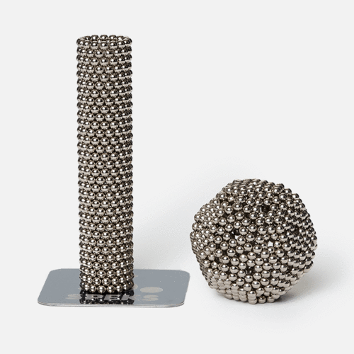cylinder stack of silver speks magnet balls and a ball made from silver magnetic balls on a white background.