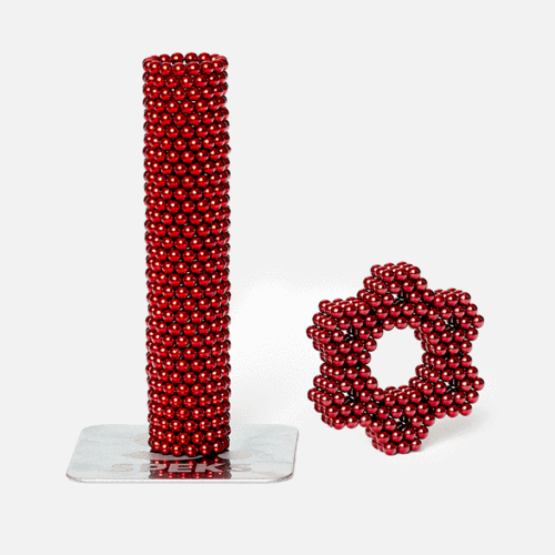 cylinder stack of red speks magnet balls and a flower shape made from red magnetic balls on a white background.
