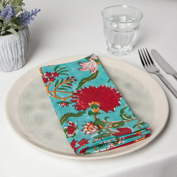 napkin folded on plate on table with glass and silverware.
