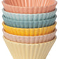 stack of solid color muffin cups: peach, light blue, blue, yellow, pink, and pale yellow.