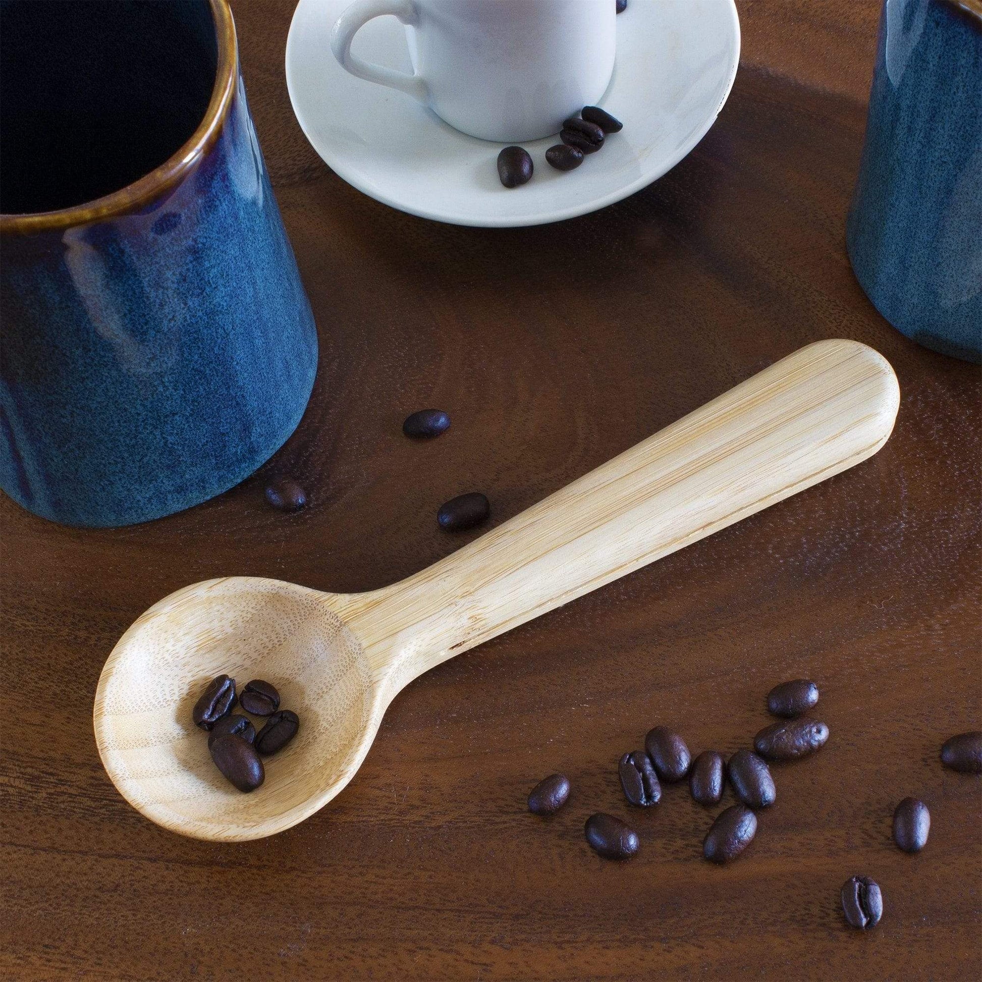 scoop on wooden table with coffee beans and mugs.