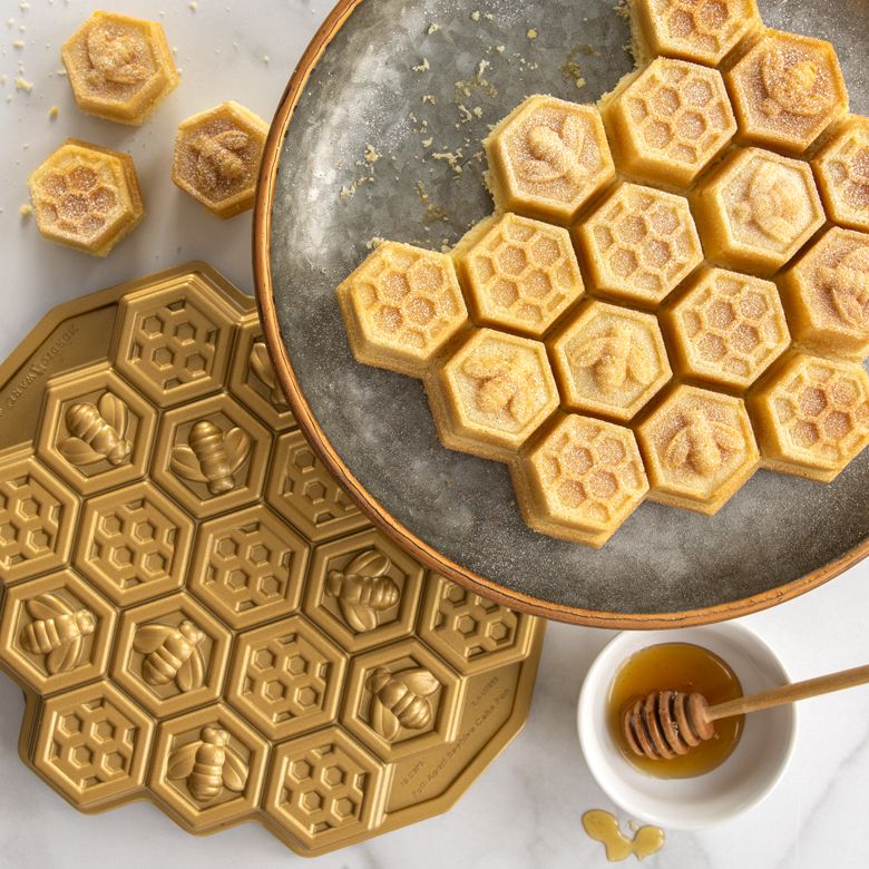 tray of honeycomb cake with pan and pot of honey next to it.
