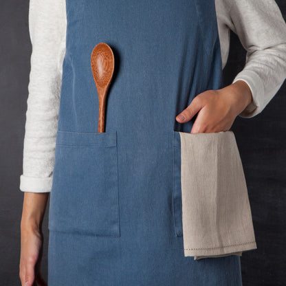 person wearing apron with wooden utensils in apron pocket.