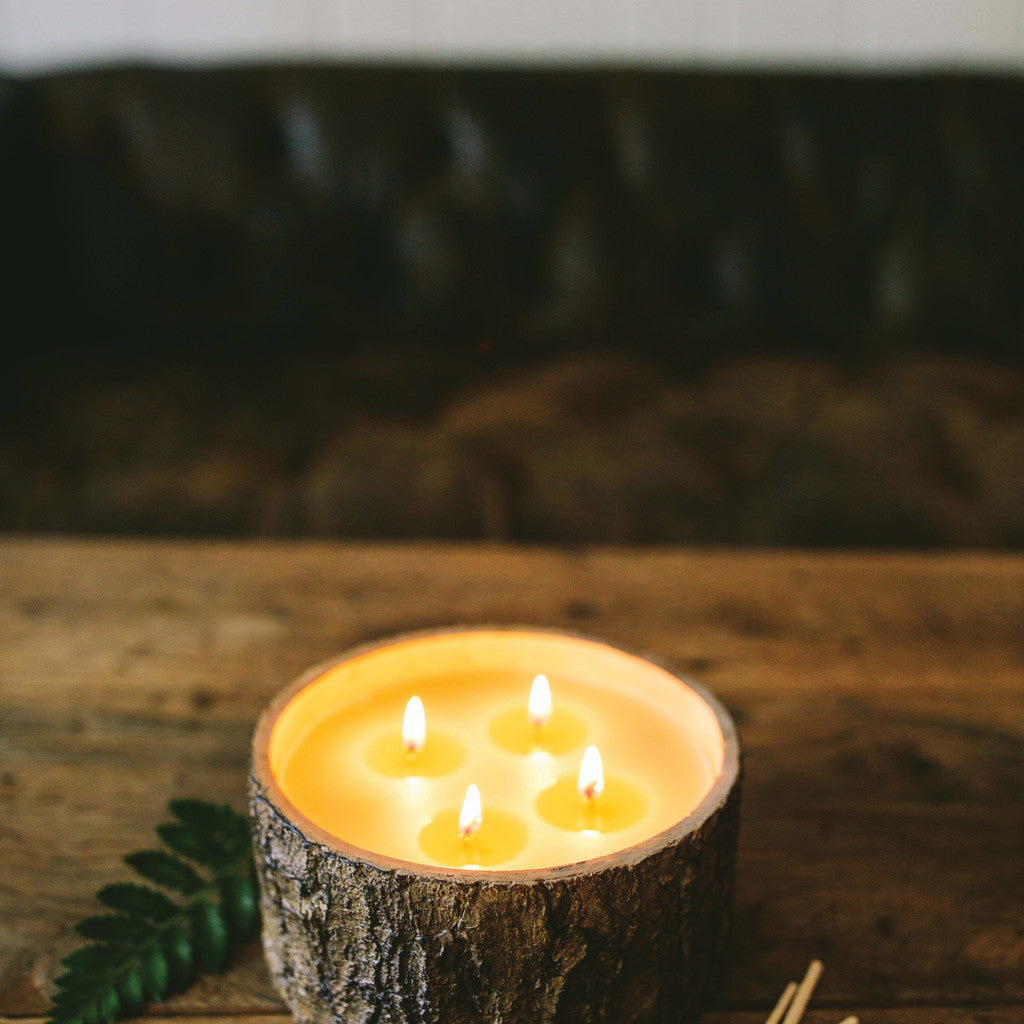 afternoon retreat candle sitting on a rustic wood table with a sofa in the background