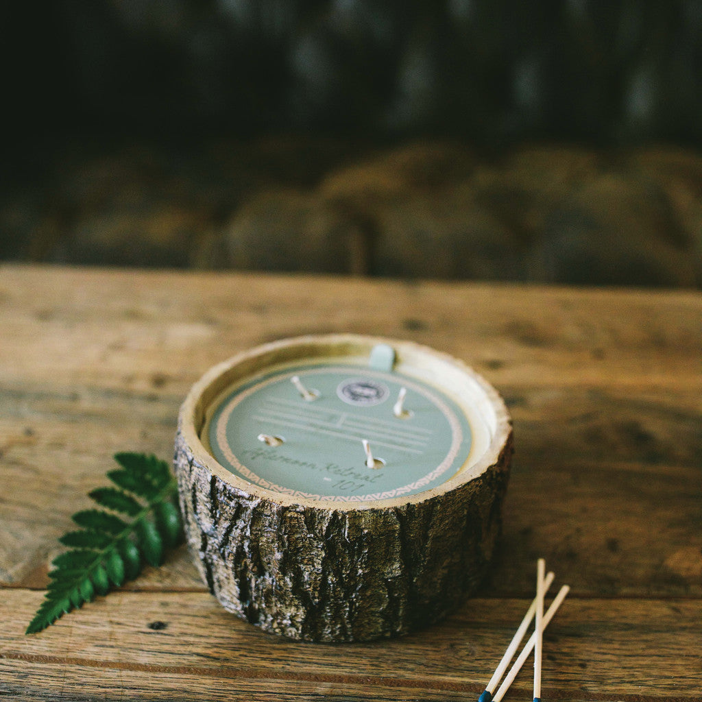 afternoon retreat candle sitting on a rustic wood table with a sofa in the background