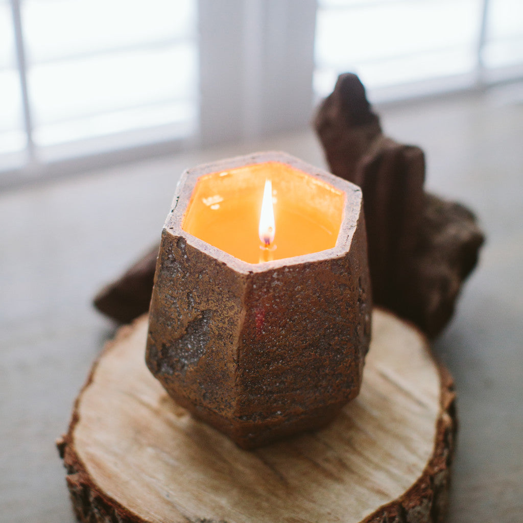 afternoon retreat candle sitting on a piece of wood near a window