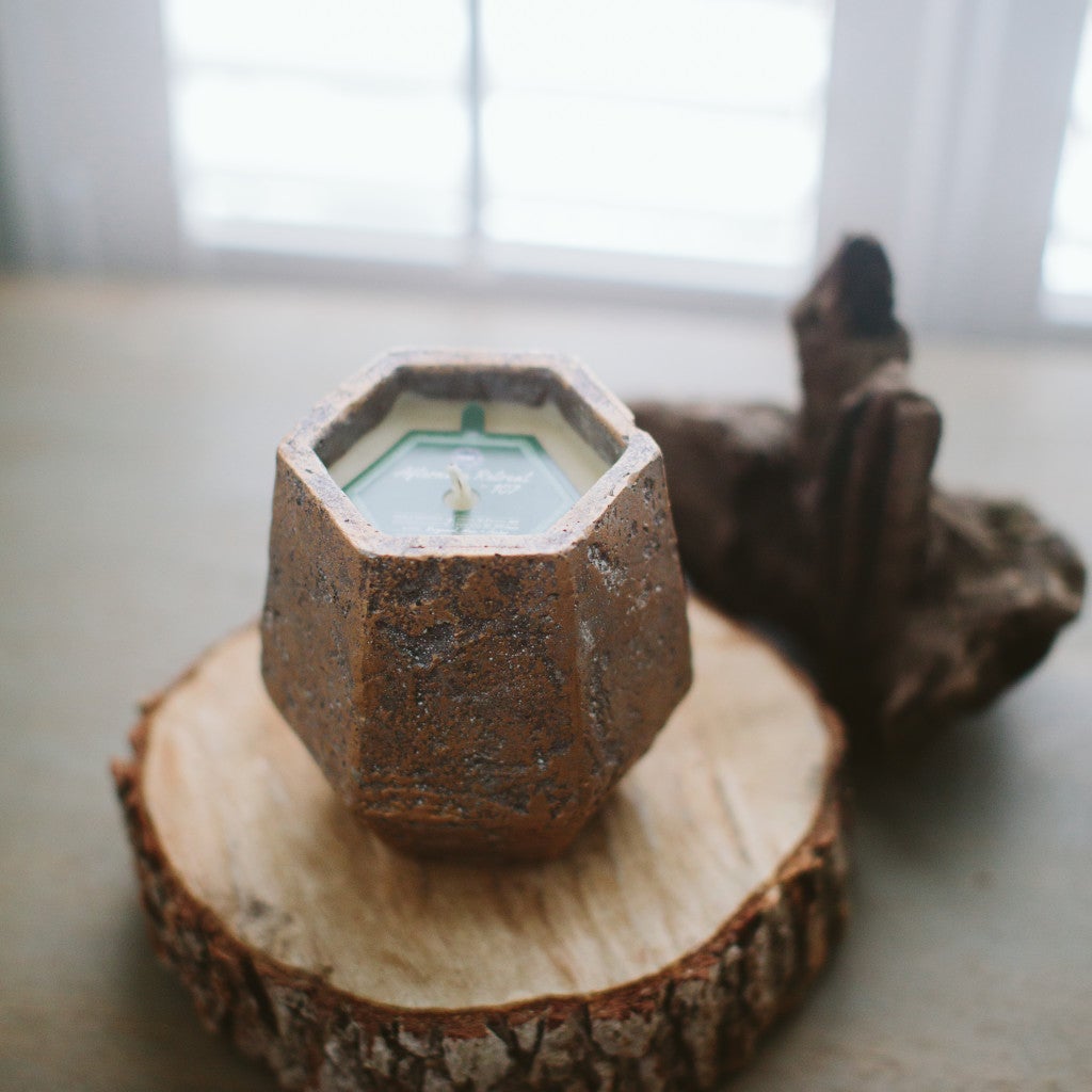 afternoon retreat candle displayed on a piece of wood near a window