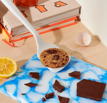 mini flip with a cookie on it over a counter with chocolate bits, egg shells, and cook books.