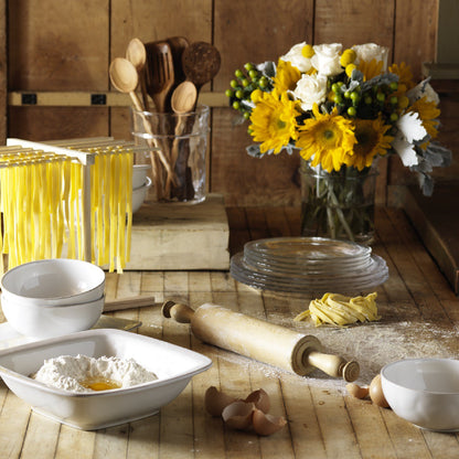 table setting with drying pasta, sunflower arrangement, rolling pin, and flower.