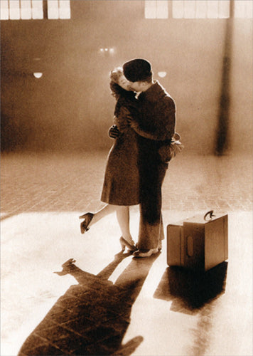 front of card is a photograph of a couple kissing with suit cases at their feet
