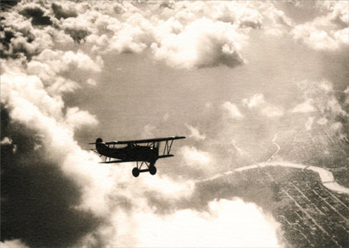 photograph of airplane in the sky with lots of clouds