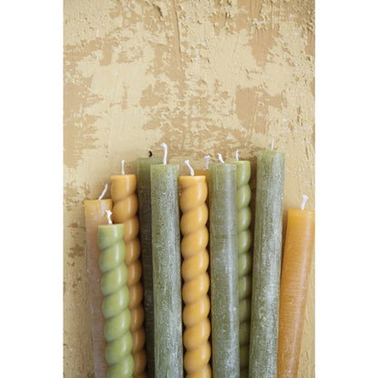 gold twisted taper candles mixed with multiple other colors on a textured tan background