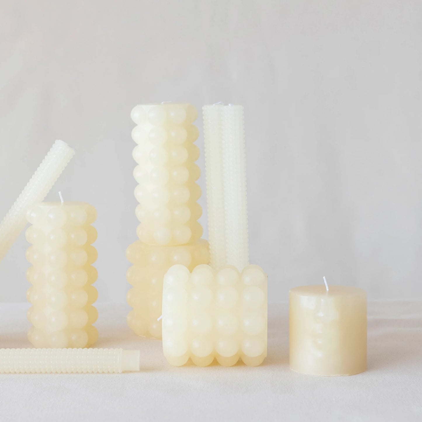 multiple sizes of pink hobnail pillar candles displayed together on against a gray background