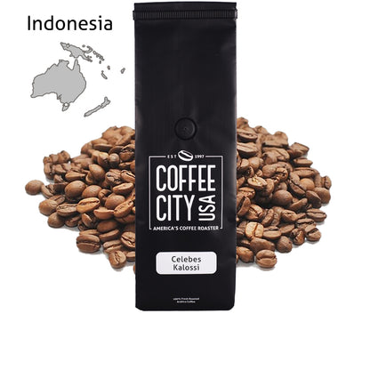 a black coffee bag filled with celebes kalossi with a pile of coffee beans behind it on a white background