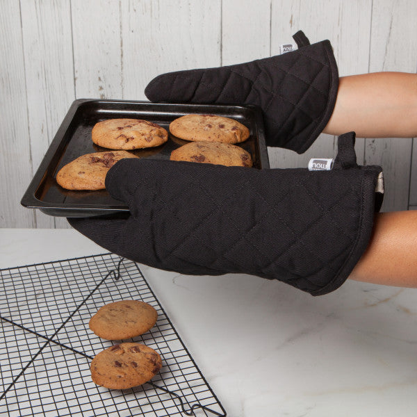hands wearing hot mitts holding baking tray of cookies.