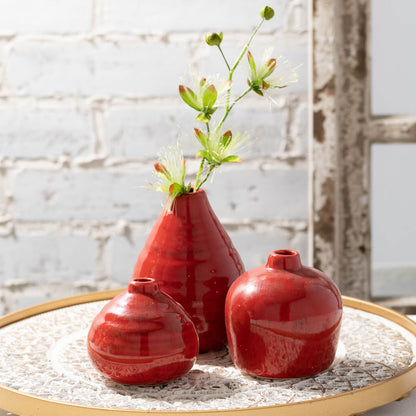 all three sizes of dappled red vases displayed on a white with gold rim tray and a flower stem in the largest one