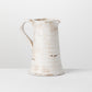 glazed ceramic pitcher on a light gray surface