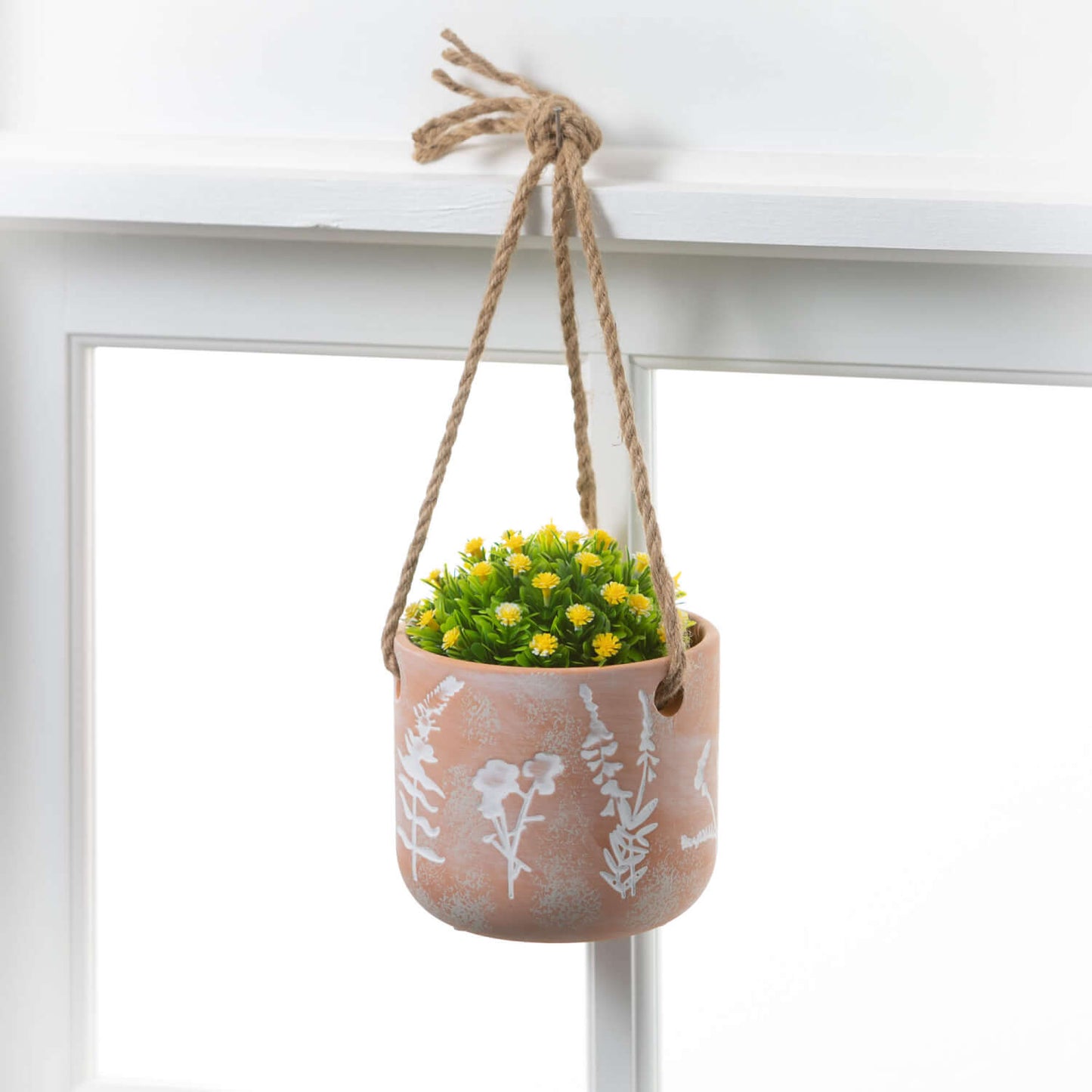 pot filled with small yellow flowers hanging in a window.