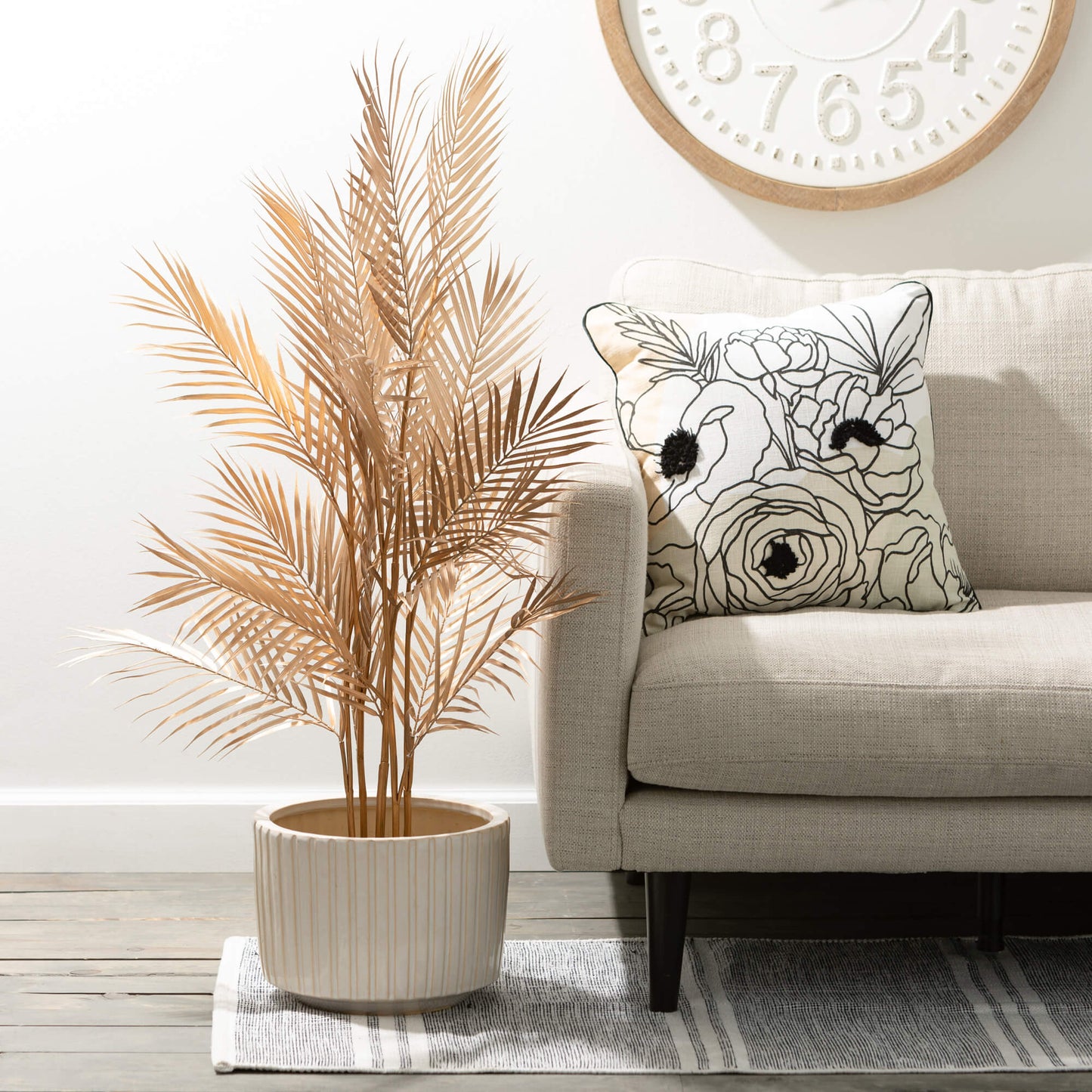 large planter with a palm in it set on the floor next to a couch.