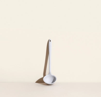 mini ladle leaning against a cream colored wall.