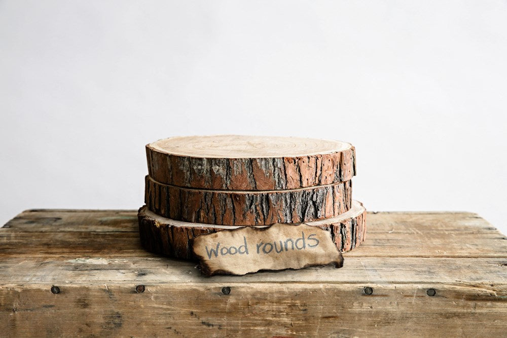 three stacked round paulownia wood slices on a rustic wood table against a white background
