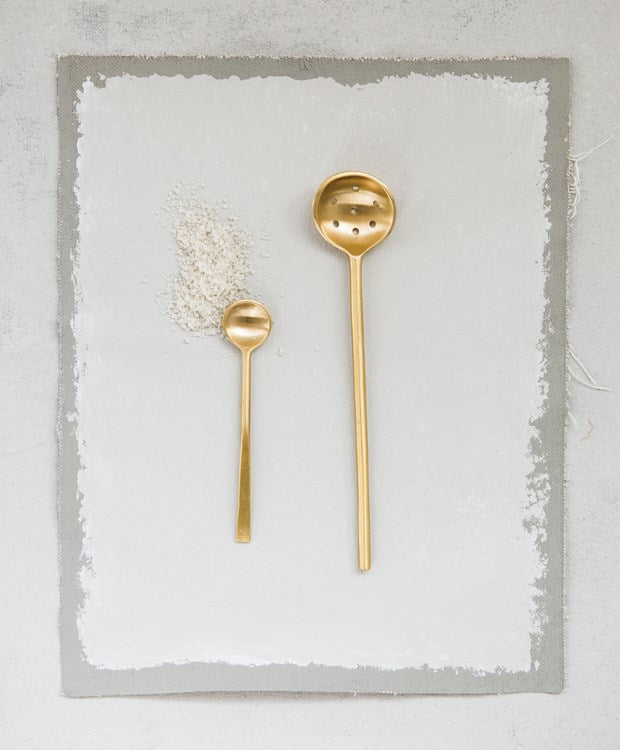 brass finish olive spoon next to a small brass spoon on a white and gray background