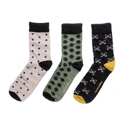  three pairs of socks, one green with shamrocks, one cream with stars, and the third is black with white keys criss-crossed. All on a white background.