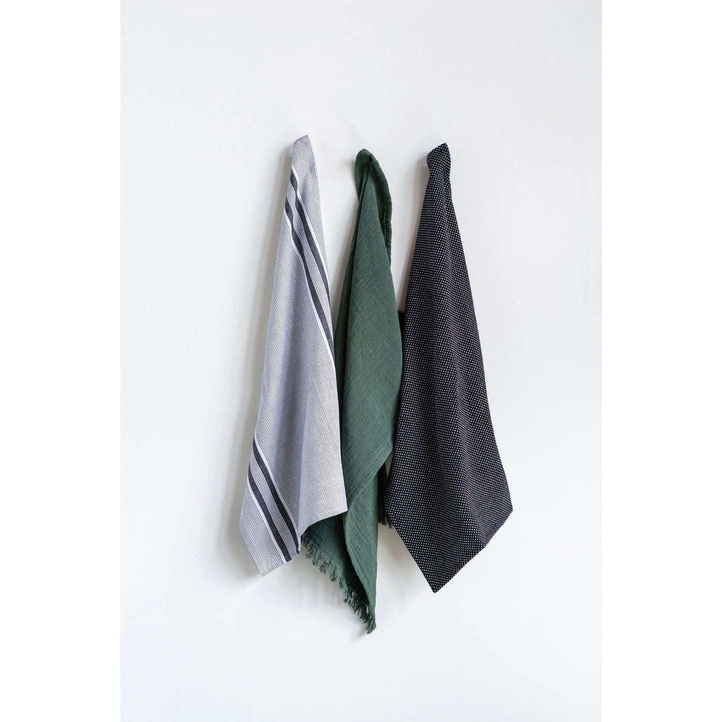 3 dish towels hanging on hooks,  1has grey and white stripes, 1 is solid green, the other is solid grey with small white dots.