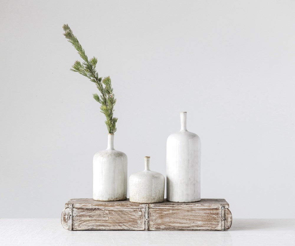 three sizes of stoneware vases displayed on a wooden block with a pine pick against a white background