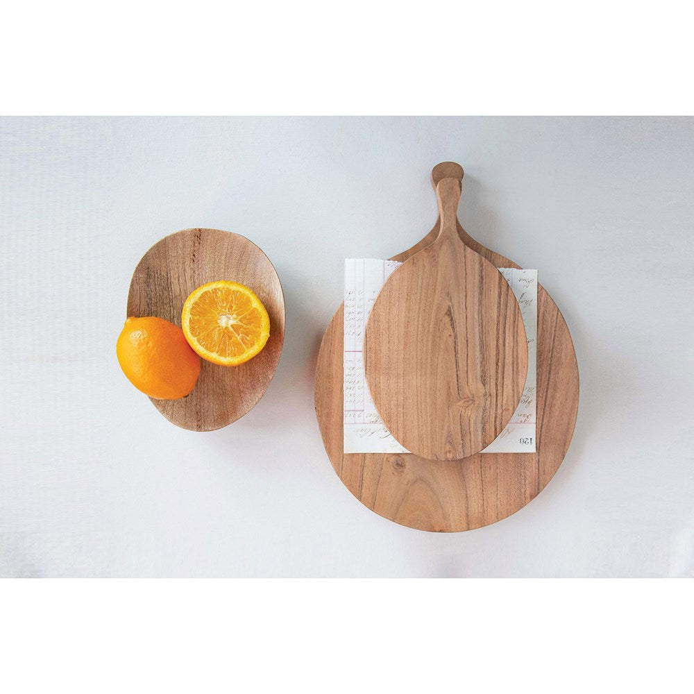 top view of acacia wood board with handles stacked with a smaller one next to a plate with sliced oranges