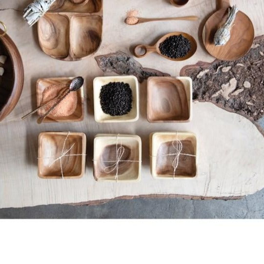 several square acacia wood bowls stacked and displayed with spices on a live edge wood slab
